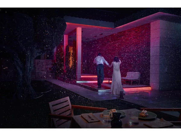 Couple standing on a rooftop at night with red lighting, surrounded by snow lit up by Philips Hue Flux Outdoor Strip Light