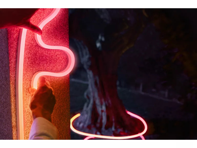 Philips Hue Neon Outdoor Strip Light being placed on wall in the dark