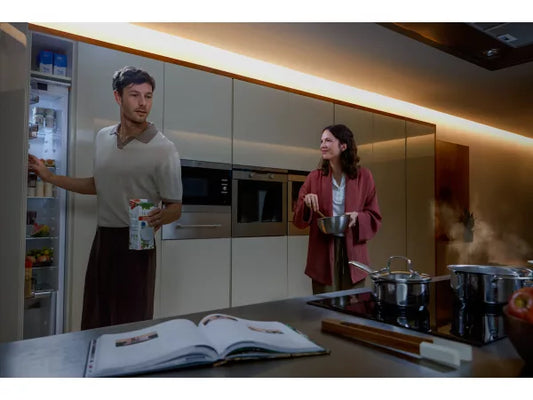 Man and woman in a kitchen with a cookbook open on the counter with the Philips Hue Flux Ultra Bright Indoor Strip Light illuminating the space
