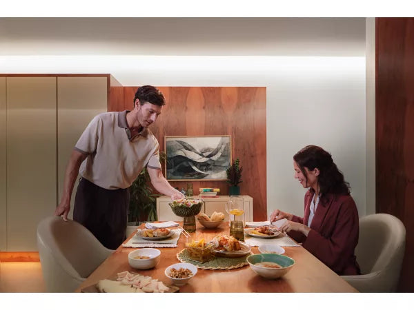 Two people sitting at a dining table with food, in a modern interior setting.
