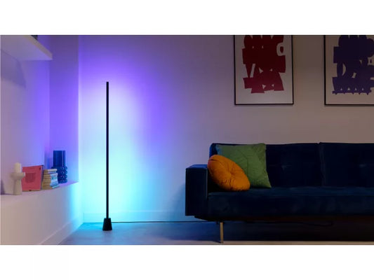 Modern living room with a colorful floor lamp casting a gradient of colors on the wall.