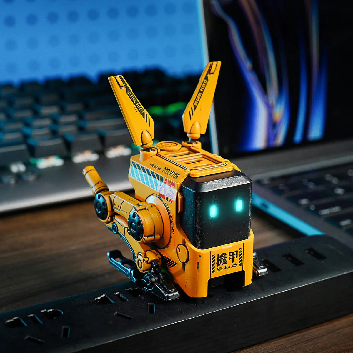 Yellow robot toy on a desk with a laptop in the background