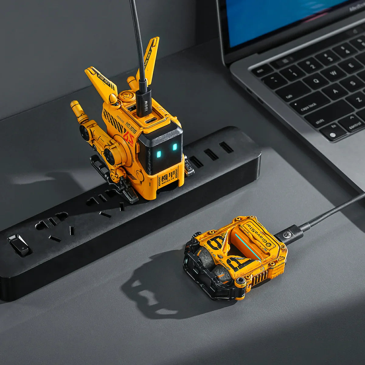Yellow remote-controlled robot on a desk with a laptop in the background
