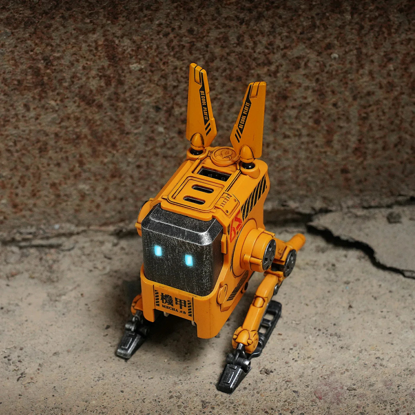 Yellow robot toy on a textured surface with a rusty metal background