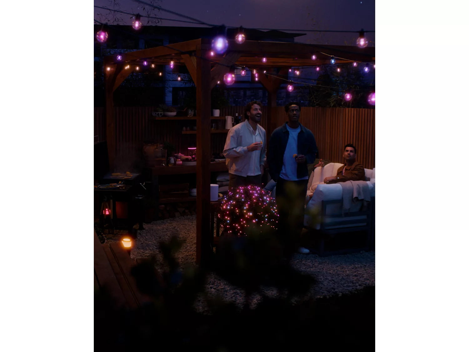 People gathered around a small tree with lights in a dark outdoor setting