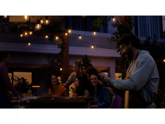 Group of people celebrating outdoors at night with hue outdoor string lights