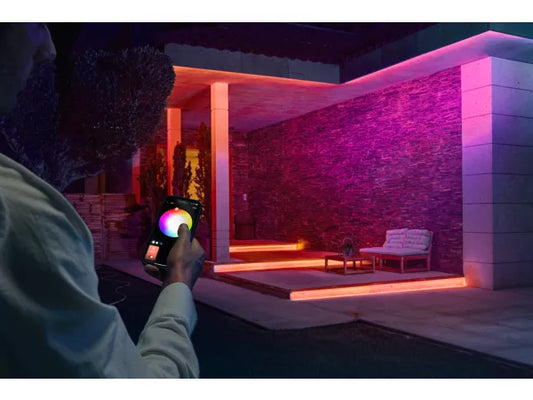 Person using a smartphone to check color temperature in a Philips Hue Flux Outdoor Strip Light with pink and purple lighting.
