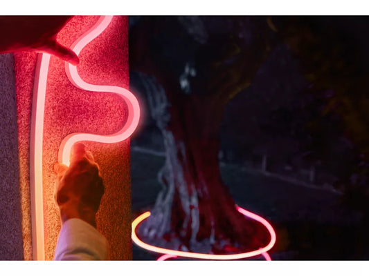 Philips Hue Neon Outdoor Strip Light being placed on wall in the dark