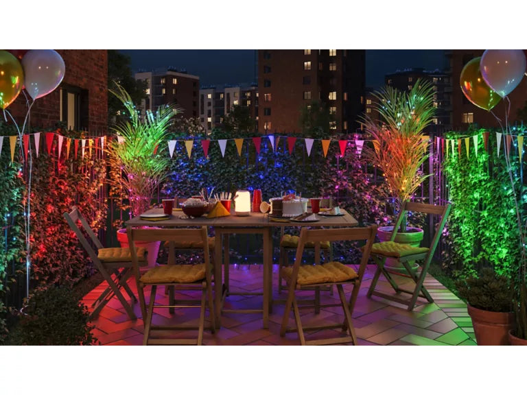 Outdoor evening setting with a table, chairs, and decorative lights on a balcony.