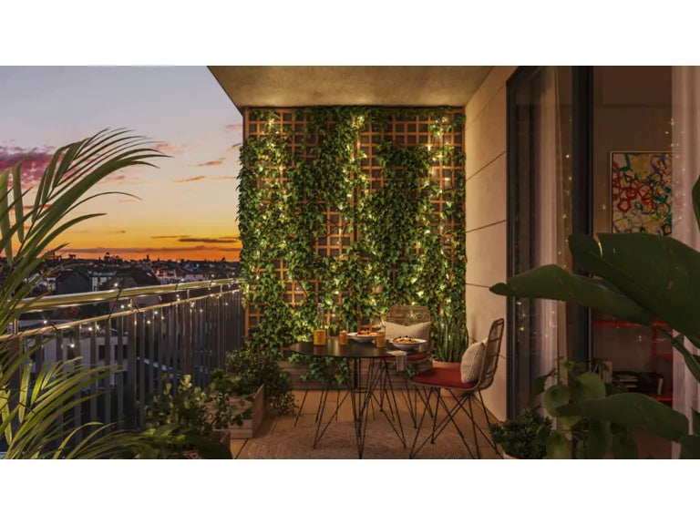 Wiz Lights Balcony with greenery, table, and chairs at sunset.
