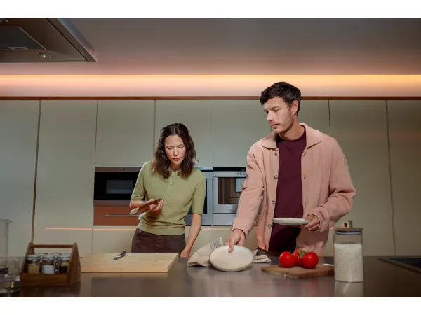 Two people in a modern kitchen preparing food with the Philips Hue Flux Ultra Bright Indoor Strip Light 