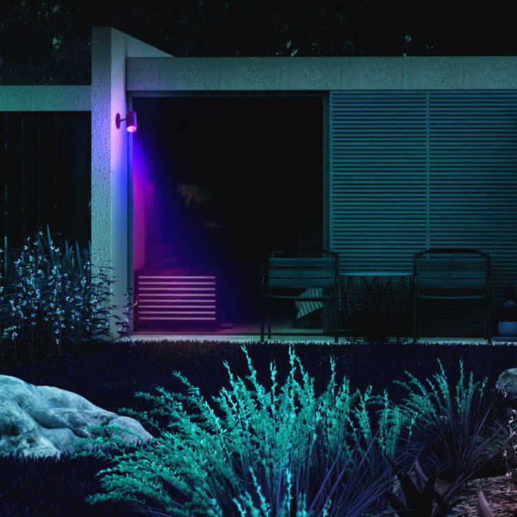 LIFX Outdoor Spot Starter Kit on a building exterior with outdoor furniture and plants at night.