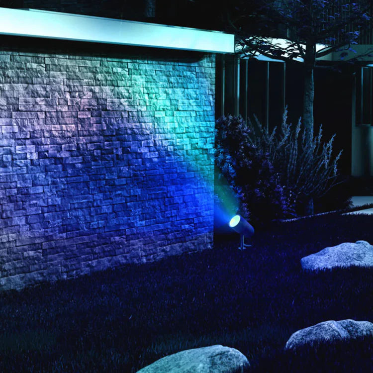 LIFX Outdoor Spot Starter Kit projecting a blue light onto a stone wall at night.