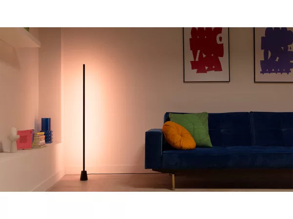 Modern living room with a blue sofa, colorful cushions, and a wiz gradient  floor lamp.